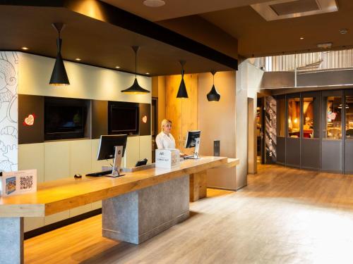 a woman standing at a reception desk in a lobby at ibis Strasbourg Centre Gare in Strasbourg