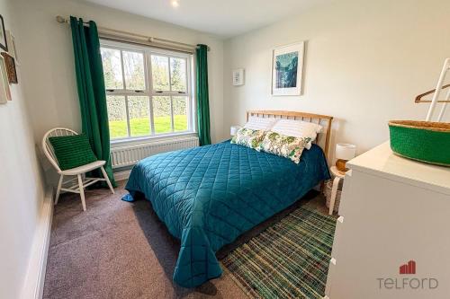 a bedroom with a bed with a green comforter and a window at Woodlodge Retreat in Holywood
