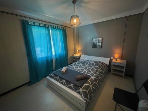 a bedroom with a bed and a window with blue curtains at CHEZ NATH ET STEPH in Le Grau-dʼAgde