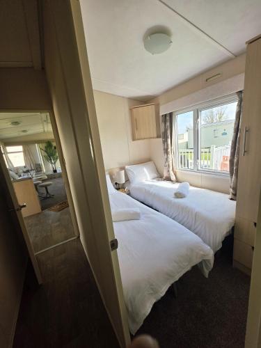 two beds in a room with a window at Loulex Deluxe in Jaywick Sands