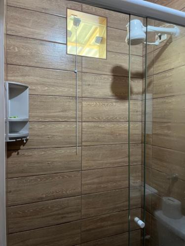 a glass shower in a bathroom with a wooden wall at Sítio Pereira in Paraty