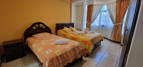 a bedroom with two beds and a window at Hospedaje Tunari - Chalet de Lujo con Jacuzzy, Jardin, Horno y Barbacoa a Leña in Quillacollo