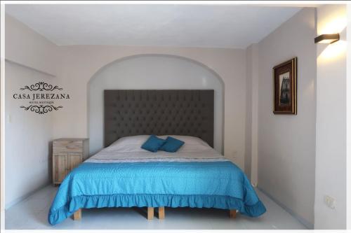a bedroom with a bed with blue pillows on it at Casa Jerezana Hotel Boutique in Jerez de García Salinas