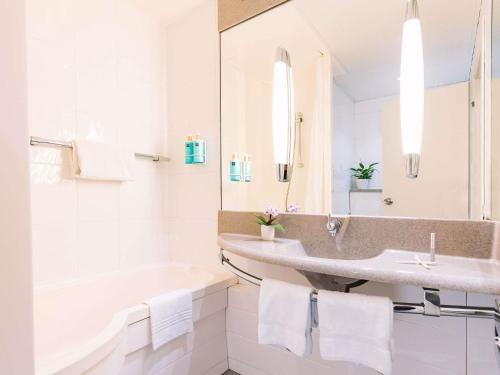 a white bathroom with a sink and a tub at Novotel Venezia Mestre Castellana in Mestre