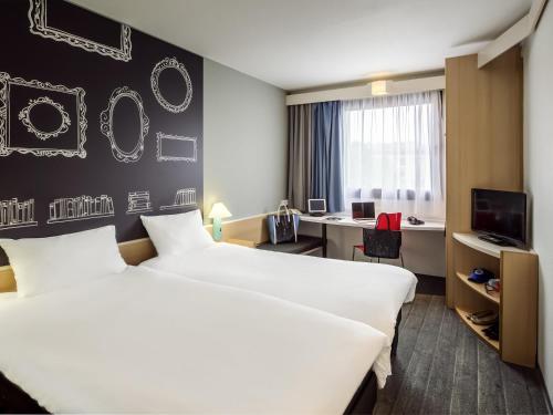 a hotel room with two beds and a desk at Ibis Szczecin Centrum in Szczecin