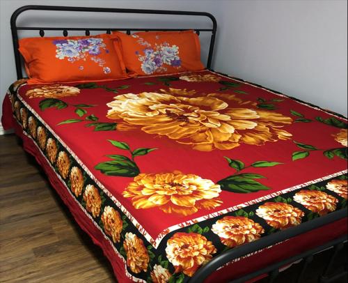 a bed with a red blanket with flowers on it at SHAY-BASEMENT-Holiday Home in Pickering