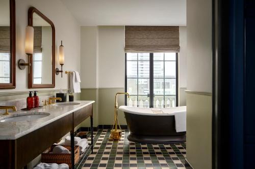 a bathroom with a tub and two sinks and a window at Cincinnati's Fidelity Hotel in Cincinnati