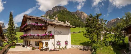 a building with flowers on the windows with mountains in the background at Pensione Haus Erica in Colfosco