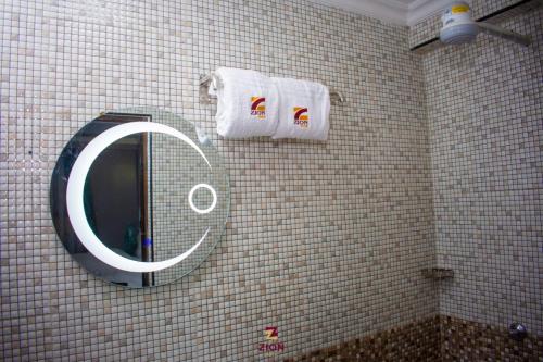 a bathroom with a mirror and towels on a tiled wall at Zion Hotel in Nakuru
