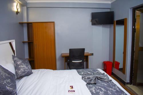 a room with a bed with a desk and a desk at Zion Hotel in Nakuru