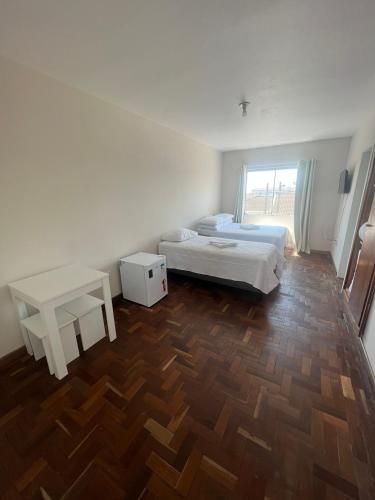 a bedroom with two beds and a wooden floor at Hotel Kruger in Tramandaí