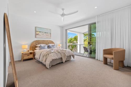 a bedroom with a bed and a chair and a window at Luxe on North Point in Kingscliff