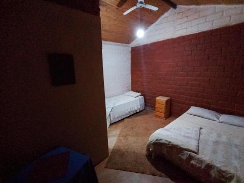 a bedroom with two beds and a brick wall at Luz da Serra Hospedagens in Santana do Riacho