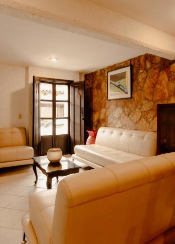 a living room with couches and a stone wall at Hotel La Antigua Express in San Cristóbal de Las Casas