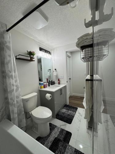 a bathroom with a toilet and a sink and a tub at Private Stylish Suite, Just Bring Your Bags in Edmonton