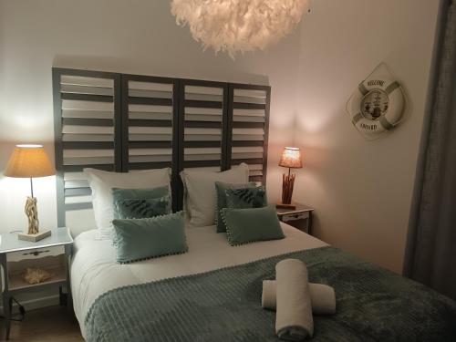 a bedroom with a large bed with green and white pillows at Le Ptit Balu, Appartement en ville, proche de Bordeaux in Bègles
