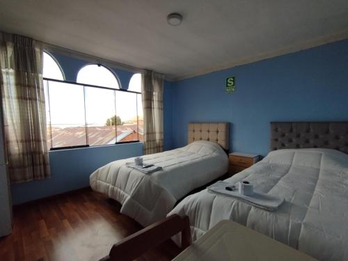 a hotel room with two beds and a window at Inti Ut'ha in Puno