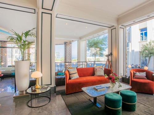 a living room with a red couch and a table at Hotel Plaza Biarritz Plage - Handwritten Collection in Biarritz