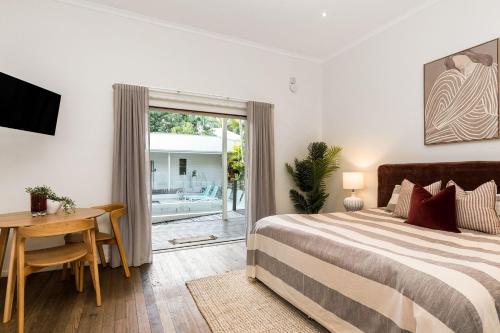a bedroom with a bed and a desk and a window at Cove Studios in Byron Bay