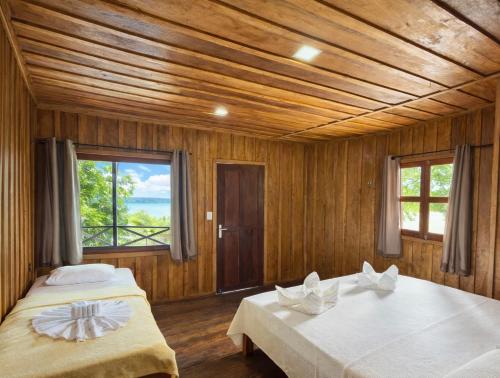 two beds in a room with wooden walls at Vista do Lago Jungle Lodge in Cajual