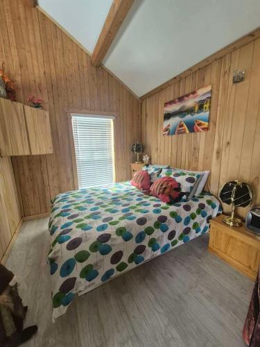 a bedroom with a bed with a comforter on it at Le Chouette Chalet in La Malbaie