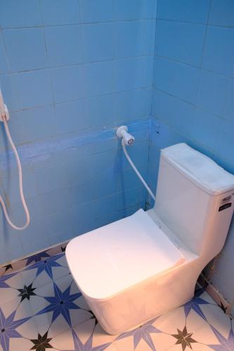 a bathroom with a white toilet in a blue wall at Aruppukottai Nadar Lodge in Chennai