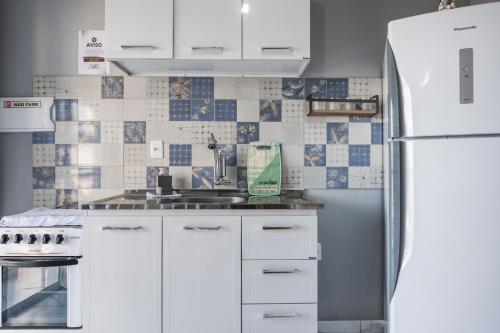 a kitchen with white cabinets and a refrigerator at Pequeno Paraíso Flats Praia Bela in Pitimbu