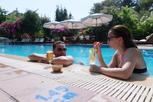 a man and a woman sitting next to a swimming pool at Mr. Dim Exclusive Apart Hotel in Göcek