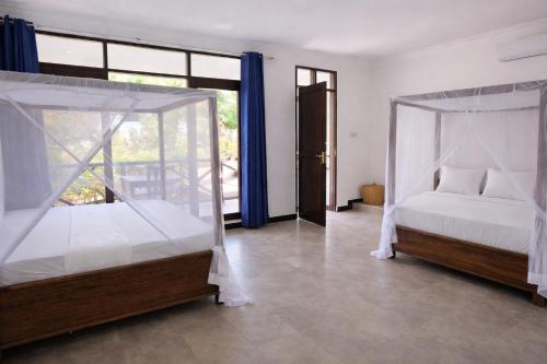 a bedroom with two beds and a large window at Majani Breeze Zanzibar in Nungwi