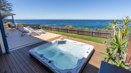 a hot tub on a deck with the ocean in the background at Bombora at Kiama in Kiama