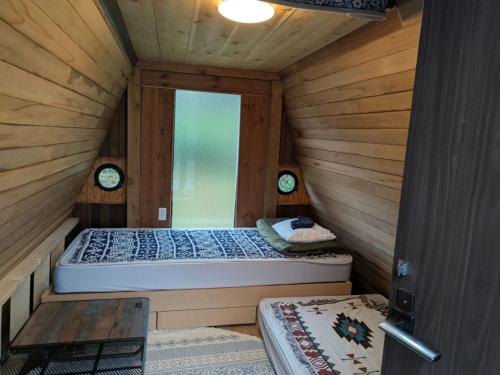 two beds in a wooden cabin with a window at ichi in Ōkasho