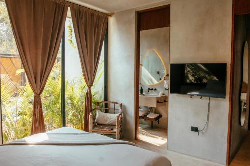 a bedroom with a bed and a window with a mirror at Villa Camila Tulum in Tulum