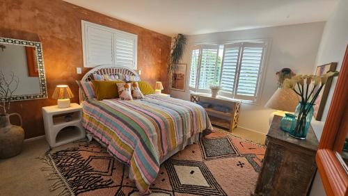 a bedroom with a bed and two lamps and windows at Bajo el Sol in Nelson