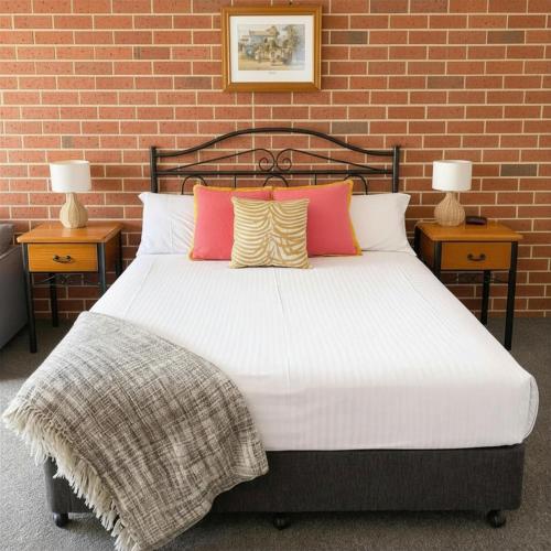 a bedroom with a bed with two tables and two lamps at Poachers Paradise in Rutherglen