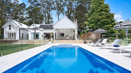 a swimming pool in front of a house at Burrawang House in Burrawang