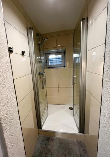 a shower with a glass door in a bathroom at Garden apartment in Ettlingen