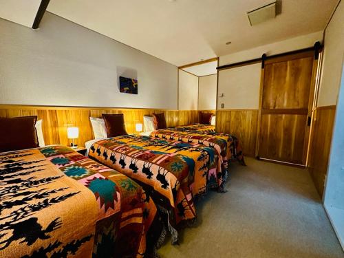 a hotel room with two beds and two lamps at Tesoro Okushiga in Yamanouchi