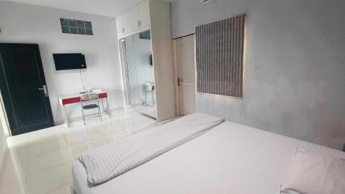 a white bedroom with a bed and a small table at Just Inn in Semarang