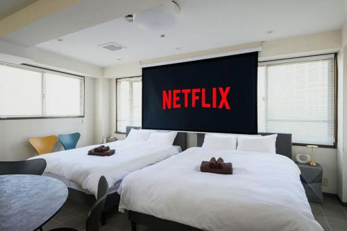 two beds in a hotel room with a netflix sign on the wall at メーイン北 in Tokyo