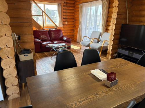 a living room with a table and a couch at 天然温泉付ログハウス ヴィレッジR 4名様まで同一料金 屋根付bbq設備あり in Shiraoi