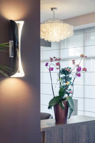 a vase of flowers sitting on a counter with a light at Mercure Hotel Brussels Centre Midi in Brussels