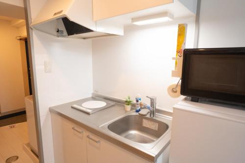 a small kitchen with a sink and a microwave at Park building Tenmonkan 1 in Kagoshima