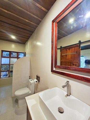 a bathroom with a sink and a toilet and a mirror at Hiên nhà Đà Lạt in Ấp Kim Thạch