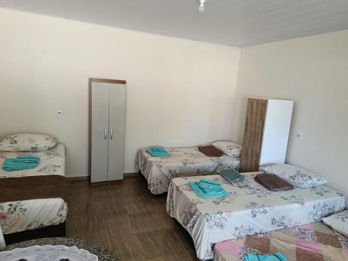a room with two beds and a door to a bedroom at Pousada Paraíso in Telêmaco Borba