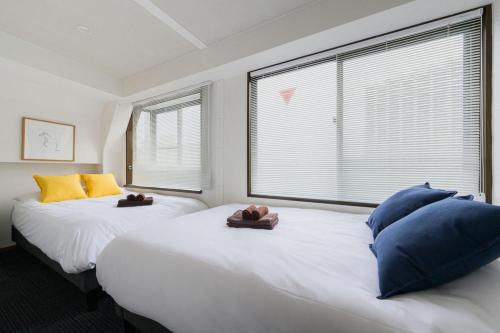 two beds in a room with two large windows at メーイン北 in Tokyo