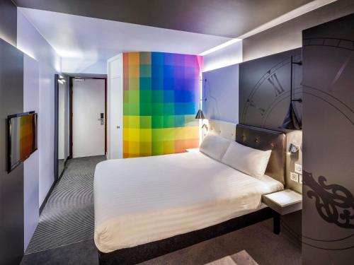 a room with a bed with a rainbow wall at ibis Styles London Southwark - near Borough Market in London