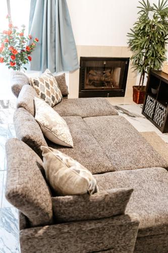a brown couch with pillows in a living room with a fireplace at The Huntsville Nest - 2BR Near SHSU - Pool - WiFi - Free Parking in Huntsville