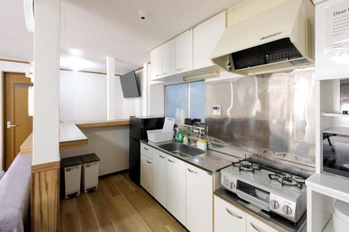 a kitchen with white cabinets and a sink and a stove at Cozy Pad in Tokyo