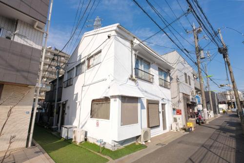 a white building on the side of a street at Cozy Pad in Tokyo