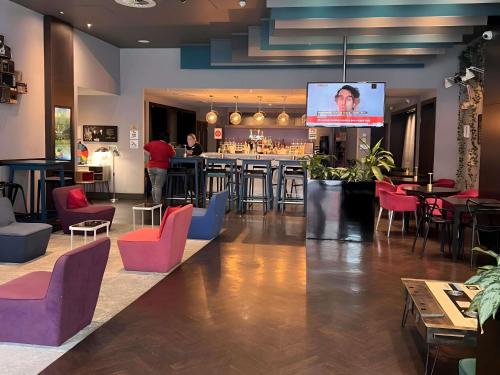 a restaurant with a bar with colorful chairs and tables at Ibis Styles Liverpool Centre Dale Street - Cavern Quarter in Liverpool